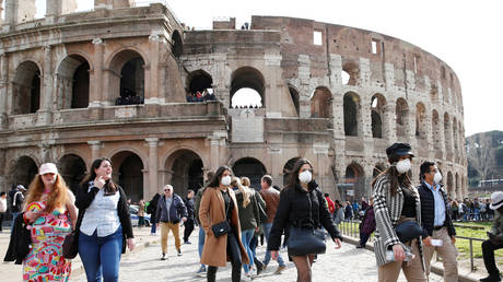 FILE PHOTO: People wearing protective masks walk past the Colosseum in Rome, Italy, February 25, 2020.