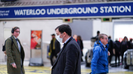FILE PHOTO: A man wearing protective face mask walks through Waterloo station, as the number of coronavirus cases grow around around the world, in London, Britain.