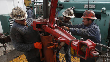 Roughnecks wrestle pipe on a True Company oil drilling rig outside Watford, North Dakota, United States