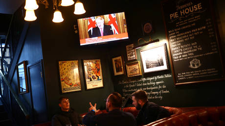 Pubgoers in London watch UK Prime Minister Boris Johnson on TV as the spread of the coronavirus disease (COVID-19) continues. March 20, 2020.