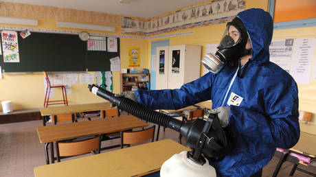 FILE PHOTO A man sprays a disinfectant against the swine flu virus on November 18, 2009 in a classroom of the Georges Brassens school in Baillargues, southern France. © AFP / Pascal Guyot