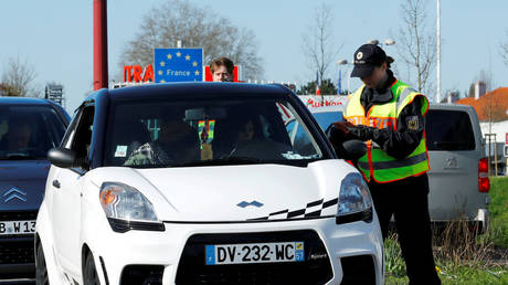 A police officer checks a car at the border with France in Saarbruecken, Germany, March 16, 2020.