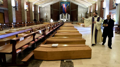A local priest blesses coffins in Seriate, Italy, as the coronavirus pandemic continues. © REUTERS/Flavio Lo Scalzo