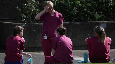 Medical staff at St Thomas' Hospital relax during a break in London, Britain, April 6, 2020. © REUTERS/Hannah McKay