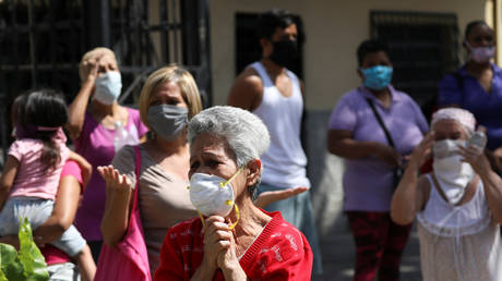 People wearing protective face masks react as The Nazarene of St Paul procession passes by in Caracas, Venezuela