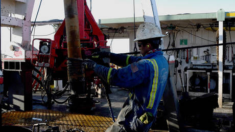A worker wrestles a stand of drill pipe into place on a drilling rig near Midland, Texas, US © Reuters / Nick Oxford