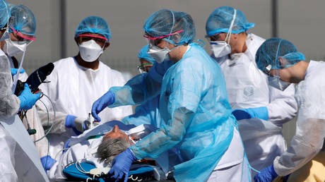 FILE PHOTO: French rescue workers in protective suits carry a patient on a stretcher as the country faces an aggressive Covid-19 outbreak.