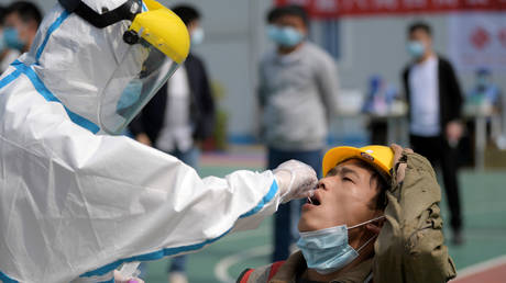 FILE PHOTO: A worker collects a swab from a construction worker in Wuhan. © China Daily via REUTERS