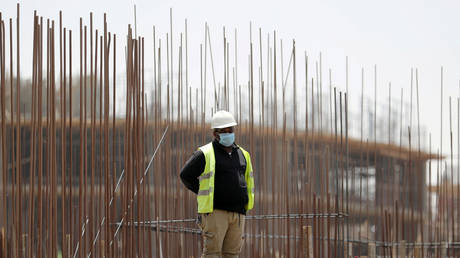 Worker wearing a protective face mask stands on a building under construction in the New Administrative Capital (NAC), east of Cairo