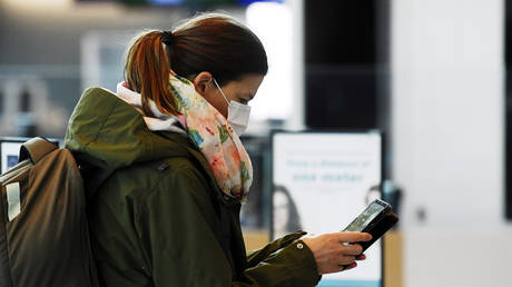 A passenger wearing a protective face mask uses a phone at Helsinki International Airport in Vantaa, Finland, May 13, 2020 © Reuters / Vesa Moilanen