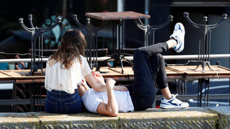 A couple sunbathes next to a closed restaurant in the Dutch city of Maastricht, March 16, 2020, © Reuters / Francois Lenoir