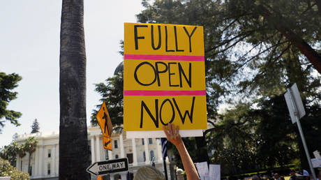 A demonstrator holds a sign during a protest calling for the reopening of California, amid the outbreak of the coronavirus disease (COVID-19), in Sacramento, California, U.S. May 7, 2020. © Reuters/Stephen Lam