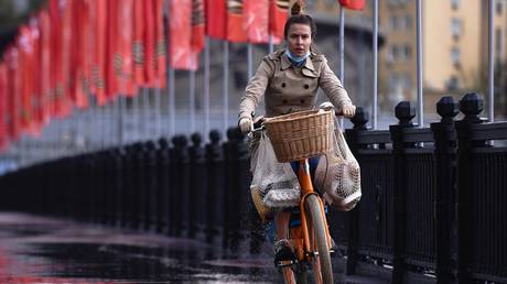 A woman rides a bicycle on Novoarbatsky bridge in Moscow