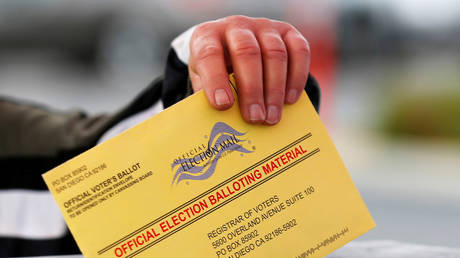 Poll worker places a mail-in ballot into voting box in San Diego, California