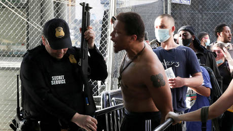 A man argues with a Secret Service officer after being pepper sprayed as demonstrators protest near the White House over the police killing of a Minneapolis man, in Washington, DC, May 29, 2020.