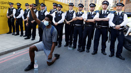 A man kneels in front of police officers during a protest near the US Embassy in London. © Reuters / John Sibley