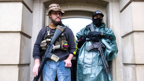 Protesters with long guns shelter during a protest against extended stay-at-home orders in Lansing, Michigan, U.S. May 14, 2020 © Reuters / Seth Herald