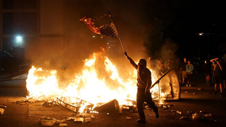 A protestor waves a burning American flag in St. Louis, Missouri, June 1, 2020.