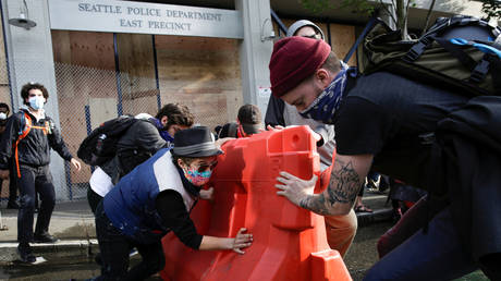 Activists maneuver a barricade outside the Seattle Police Department's abandoned East Precinct in the 'Capitol Hill Autonomous Zone', Seattle, Washington, June 8, 2020.