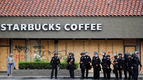 Police officers stand in front of a boarded up Starbucks shop during a demonstration in Anaheim, California