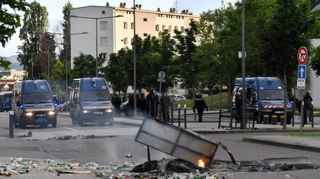 Gendarmes stand near their vehicles as burning trash in the street in the Gresilles area of Dijon, eastern France, on June 15, 2020 ©  AFP / Philippe DESMAZES
