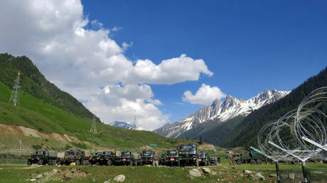 Indian army soldiers walk past their parked trucks at a makeshift transit camp before heading to Ladakh, near Baltal, southeast of Srinagar, June 16, 2020