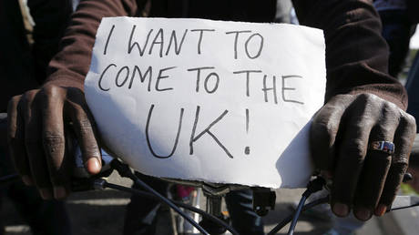 FILE PHOTO: A migrant holds a placard which reads "I want to come to the UK" on his bicycle at the makeshift camp called "The New Jungle" in Calais, France. © Reuters / Regis Duvignau
