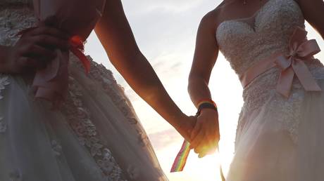 FILE PHOTO. A newlywed lesbian couple in wedding dresses holds hands, May 25, 2019