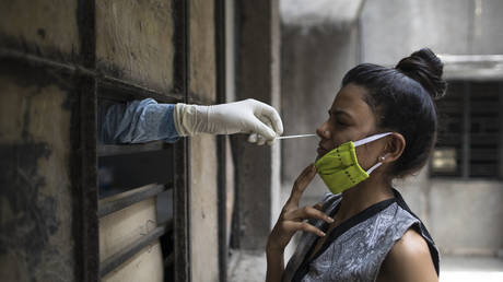 A health official collects a swab sample from a woman at a free testing facility in New Delhi, June 19, 2020 © AFP / XAVIER GALIANA