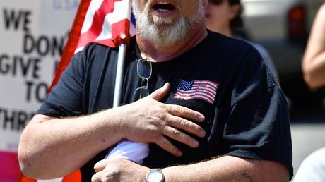 A demonstrator crosses his heart while singing the National Anthem before a protest rally outside the Pennsylvania Capitol Building, on May 15, © Getty Images / Mark Makela