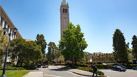 A young male student walks past Sather Tower and other campus buildings on a sunny day on the main campus of UC Berkeley in downtown Berkeley, California, May 21, 2018. © Getty Images/Smith Collection/Gado