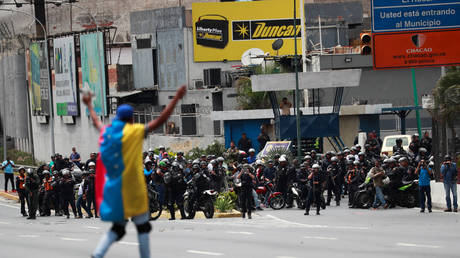 FILE PHOTO: A demonstrator covered with a Venezuelan flag gestures in front of the security forces during a protest in Caracas, Venezuela March 10, © REUTERS/Carlos Jasso