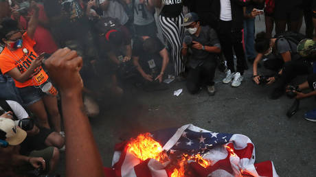 A group of protesters burn an American flag during a protest against racial inequality and police violence near Black Lives Matter Plaza, during Fourth of July holiday, in Washington, U.S., July 4, 2020. © REUTERS/Leah Millis