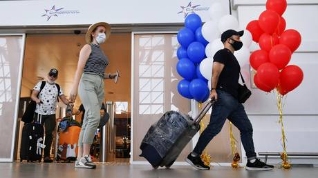 Tourists wearing face masks are pictured at Simferopol International Airport, Crimea, Russia. © Sputnik / Konstantin Mihalchevskiy