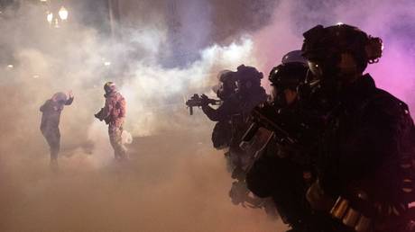 Federal law enforcement officers fire tear gas and other munitions to disperse protesters during a demonstration against police violence and racial inequality in Portland, Oregon, July 30, 2020.