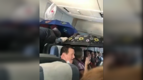 The wet set: WATCH passengers sheltering under umbrellas as 'rain' falls INSIDE airborne plane