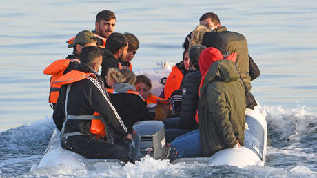 FILE PHOTO: A dingy carries a group of migrants is escorted to the English Border Force by a French patrol boat on the English Channel, 12 miles from Dover on May 27, 2020 at sea
