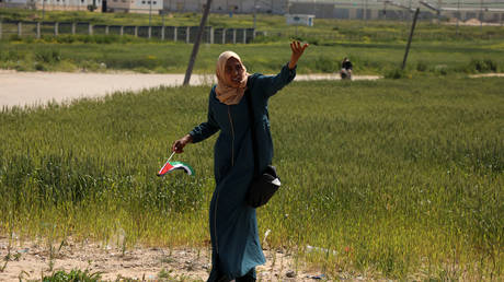 FILE PHOTO: A woman holds a Palestinian flag during an event marking Land Day near the Israel-Gaza border as mass rallies planned to commemorate the event were cancelled amid concerns about the spread of coronavirus disease (COVID-19), east of Gaza City March 30, 2020