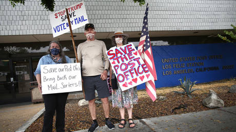 People hold up signs supporting the U.S. Postal Service and right to vote by mail on August 15, 2020 in Los Angeles, California