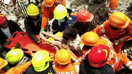 The four-year-old boy with his rescuers after he was pulled from the site of a collapsed building in Mahad, India, August 25, 2020. © NDRF/AFP