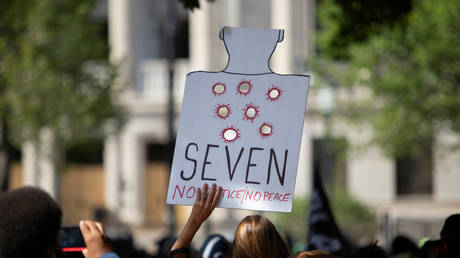 A protester holds a sign in Civic Center Park during speeches given by Jacob Blake's family, and organizers of the march, in Kenosha, Wisconsin, U.S., August 29, 2020. © REUTERS/Jim Vondruska