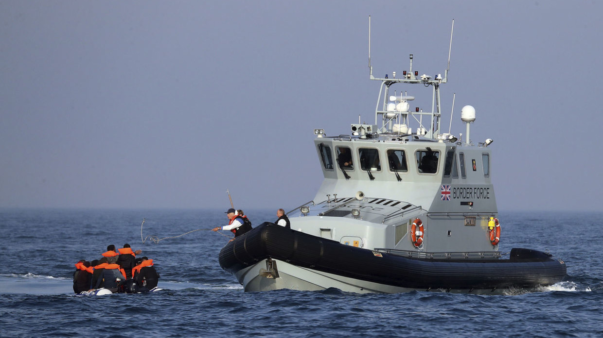 A Border Force vessel assist a group of people thought to be migrants on board from their inflatable dinghy in the Channel, Monday Aug. 10, 2020.