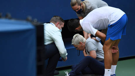 Novak Djokovic of Serbia and a US Open tournament official tend to a linesperson who was struck with a ball by Djokovic, Sep 6, 2020