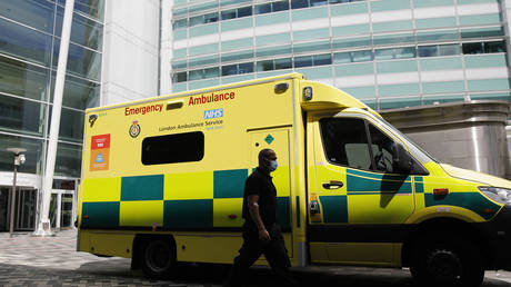 FILE PHOTO: A man walks past an ambulance at University College Hospital in London on July 17, 2020. © Tolga Akmen / AFP
