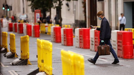 A man wearing a face mask crosses a road laid out with social distancing barriers in the City of London © REUTERS/John Sibley