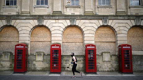 FILE PHOTO: A man wearing a mask jogs past red phone boxes in Blackpool town centre as people and businesses observe the pandemic lockdown and stay home on April 02, 2020 in Blackpool, England.