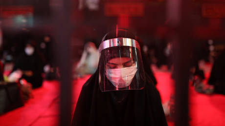 An Iranian Shiite Muslim woman wears a face shield in Tehran, Iran