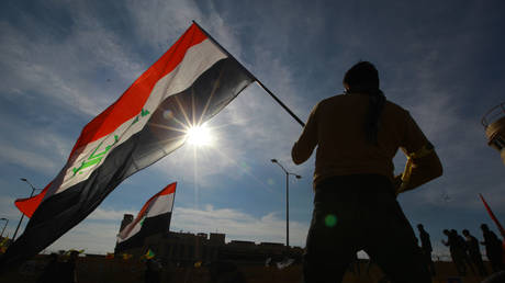 A protester holds an Iraqi flag during a sit-in in front of the US embassy against deadly US airstrikes on Shiite militia in Baghdad, Iraq, 01 January 2020 © Global Look Press/ dpa/ Ameer Al Mohmmedaw