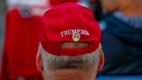 A man has a Jesus Christ pin affixed to a Trump 2020 hat during a Make American Great Again rally with Eric Trump