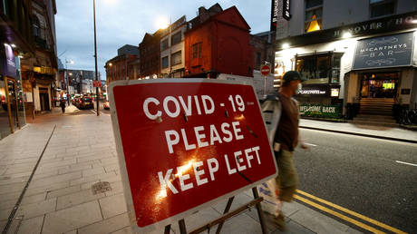 A man walks past a signage in Liverpool City Centre as Merseyside remains under lockdown due to the coronavirus disease (COVID-19) outbreak, in Liverpool, Britain